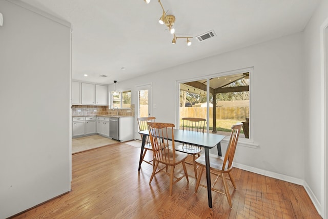 dining room featuring light wood-type flooring, visible vents, and baseboards