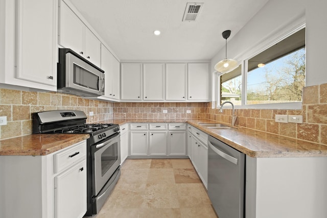 kitchen with visible vents, white cabinets, stainless steel appliances, pendant lighting, and a sink