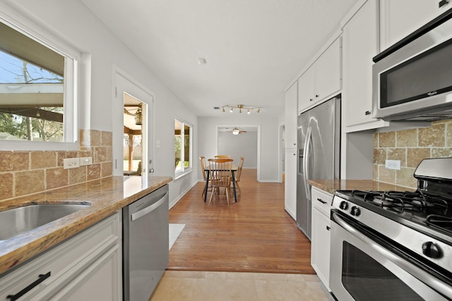 kitchen featuring appliances with stainless steel finishes, plenty of natural light, backsplash, and white cabinets