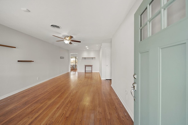 unfurnished living room featuring a ceiling fan, visible vents, baseboards, and wood finished floors