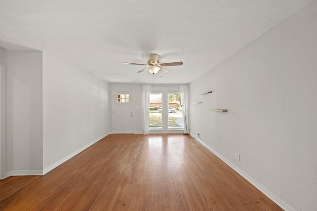 spare room featuring ceiling fan, baseboards, and wood finished floors