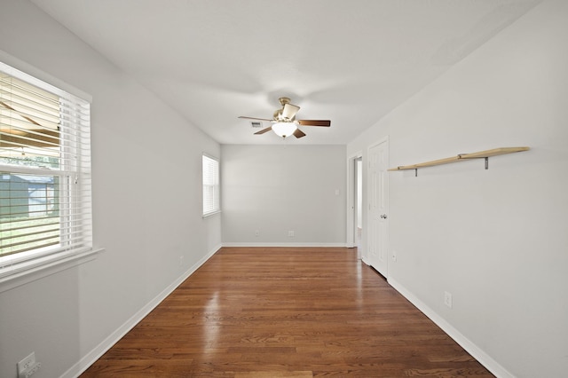 empty room with dark wood-style floors, ceiling fan, and baseboards