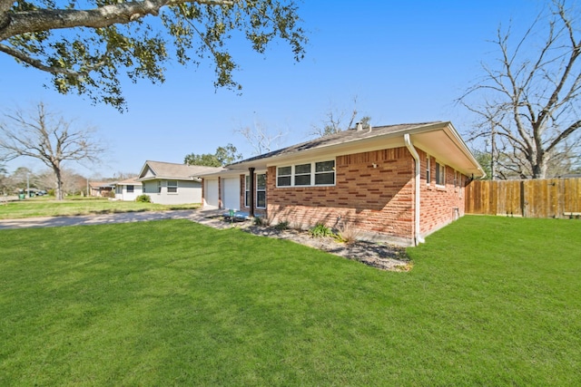 back of property featuring an attached garage, brick siding, fence, driveway, and a lawn