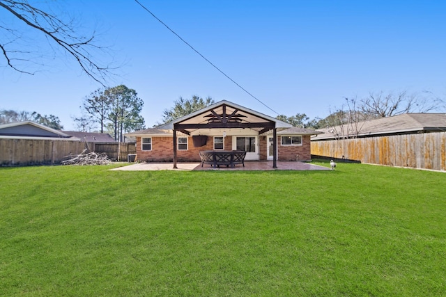 rear view of house featuring a yard, a fenced backyard, brick siding, and a patio