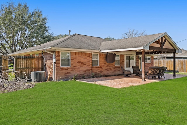 back of property featuring brick siding, a yard, a patio area, fence, and central AC