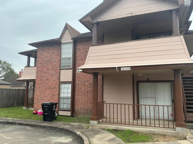 view of front of house with fence, a porch, and brick siding