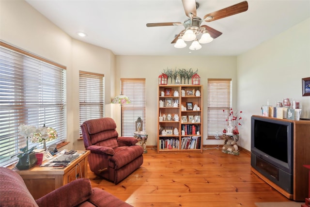 living area featuring baseboards, a ceiling fan, and light wood-style floors