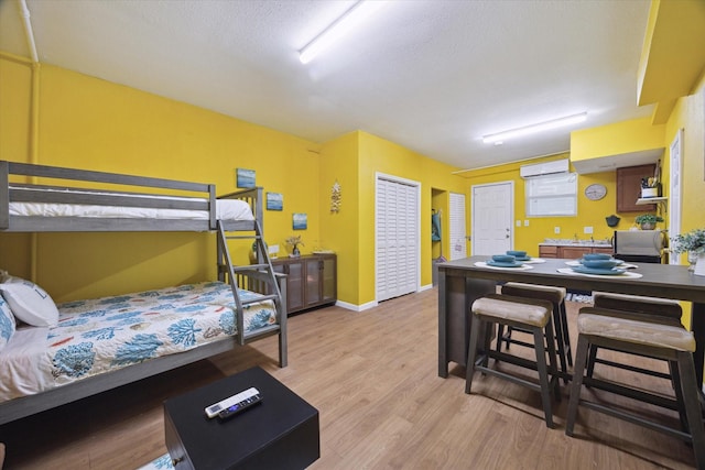 bedroom with light wood finished floors, baseboards, and a textured ceiling