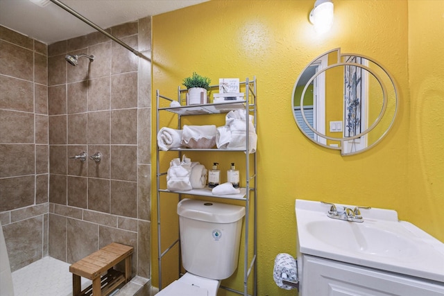 bathroom with a tile shower, vanity, and toilet