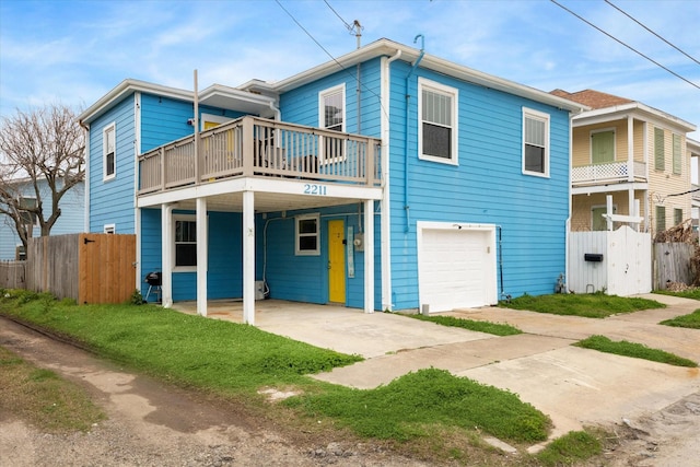 view of front of property featuring a garage, driveway, a balcony, fence, and a carport