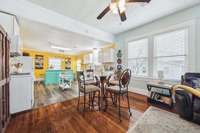 dining area with ceiling fan, ornamental molding, dark wood-style flooring, and baseboards