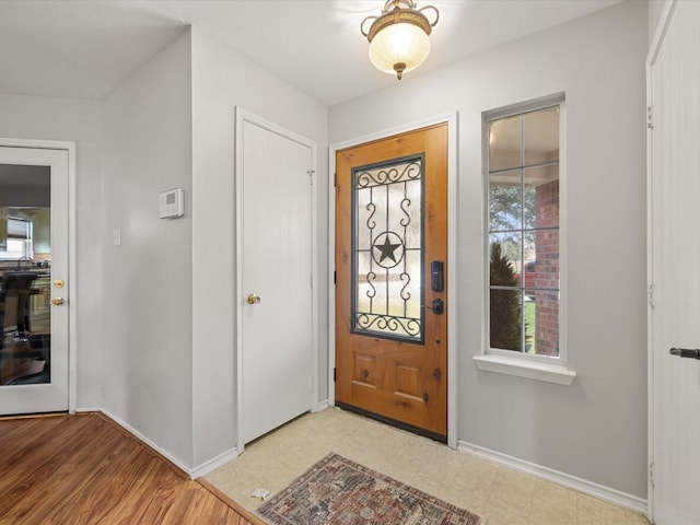 foyer entrance with baseboards and light floors