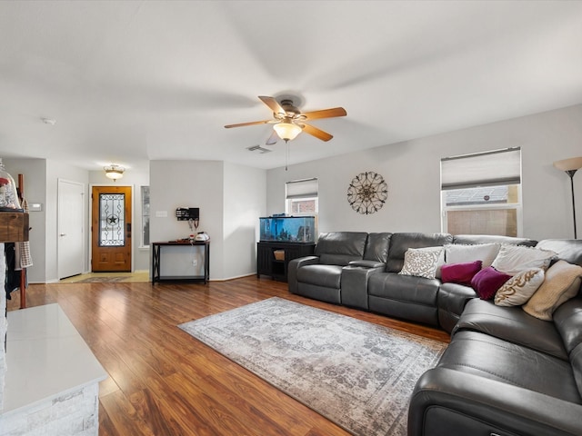 living area featuring visible vents, a fireplace, a ceiling fan, and wood finished floors