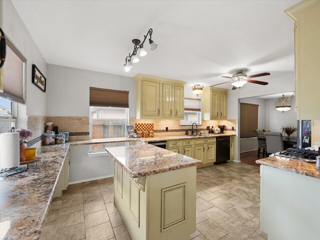 kitchen with a sink, tasteful backsplash, cream cabinets, and light stone countertops