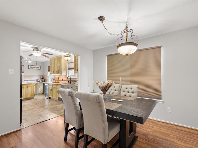 dining space with baseboards, wine cooler, light wood-style floors, and ceiling fan