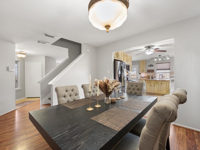 dining room with visible vents, light wood-style flooring, stairs, and ceiling fan