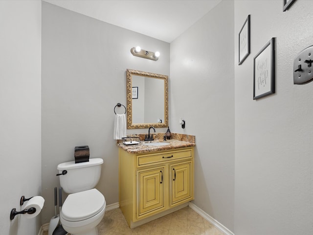 bathroom featuring baseboards, toilet, and vanity