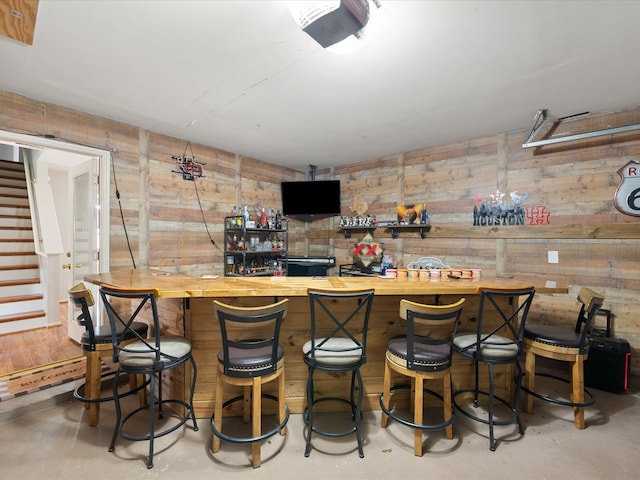 bar with stairway, concrete floors, and indoor bar