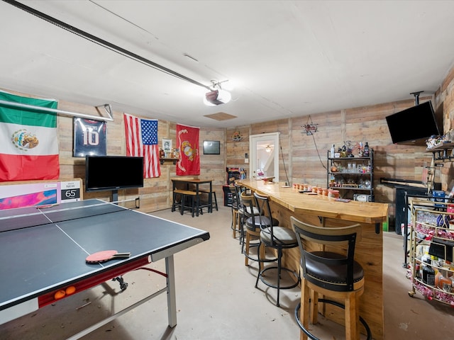 playroom featuring a dry bar, wood walls, and concrete floors