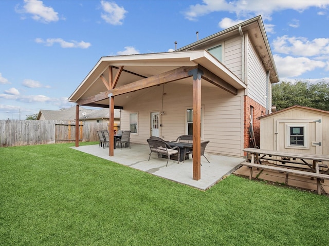 rear view of house with an outbuilding, fence, a lawn, a patio area, and brick siding