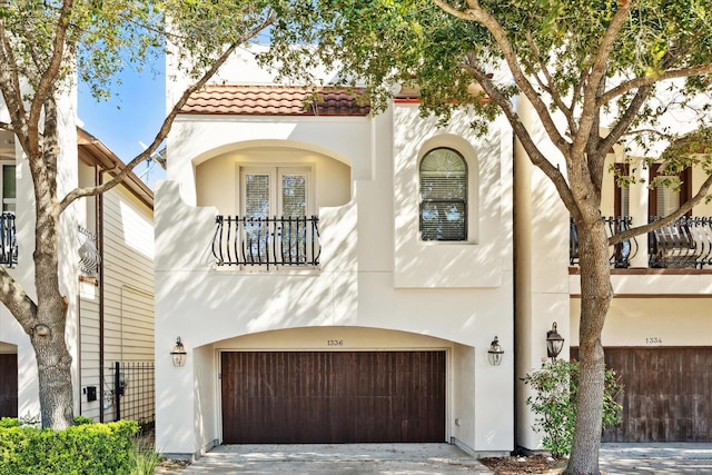 mediterranean / spanish-style home with a garage, driveway, a tile roof, and stucco siding