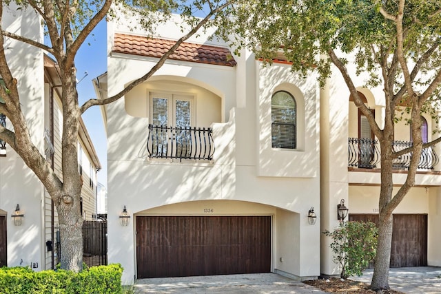 mediterranean / spanish house featuring an attached garage, a tile roof, and stucco siding