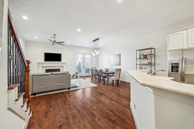 kitchen with decorative light fixtures, dark wood finished floors, a fireplace, white cabinetry, and stainless steel fridge