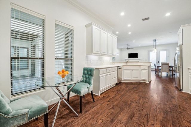 kitchen featuring appliances with stainless steel finishes, open floor plan, a peninsula, hanging light fixtures, and light countertops