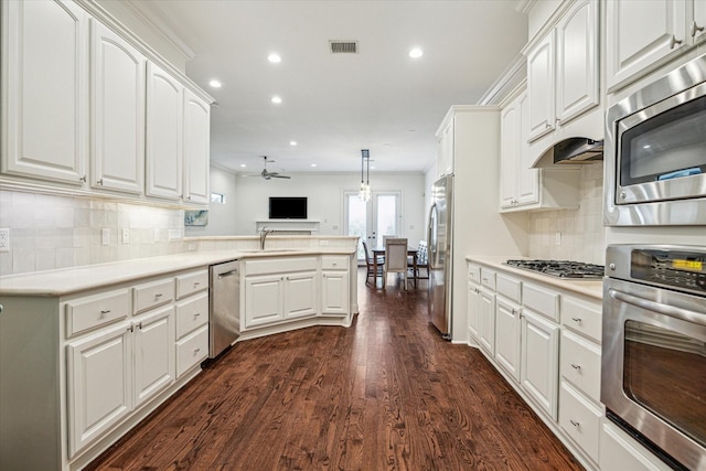 kitchen with a peninsula, appliances with stainless steel finishes, light countertops, and pendant lighting