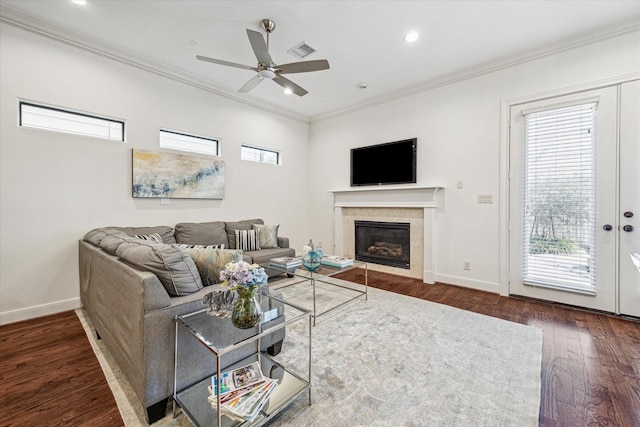 living room featuring dark wood-style flooring, crown molding, visible vents, a tile fireplace, and baseboards