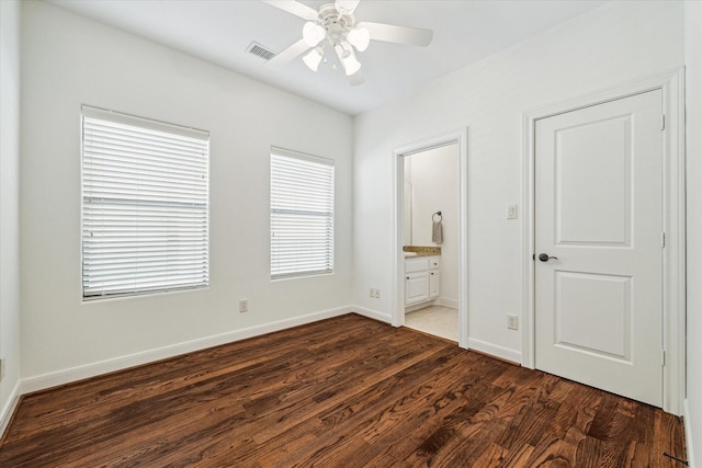 unfurnished bedroom with dark wood finished floors, visible vents, a ceiling fan, connected bathroom, and baseboards