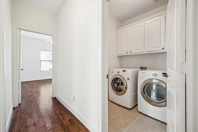 laundry room featuring light wood-type flooring, cabinet space, baseboards, and washer and dryer