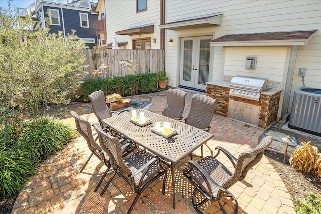 view of patio / terrace featuring outdoor dining area, an outdoor kitchen, a grill, fence, and french doors