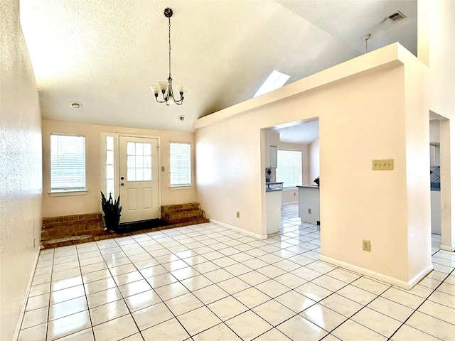 foyer entrance with lofted ceiling, an inviting chandelier, plenty of natural light, and light tile patterned flooring