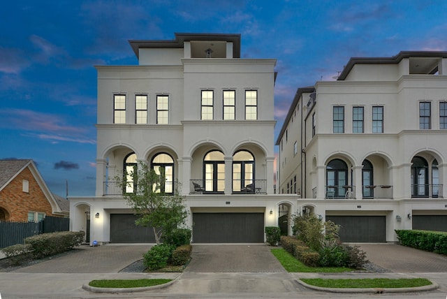 view of front of home with french doors, decorative driveway, an attached garage, and stucco siding