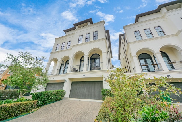 view of front of home with a garage, decorative driveway, a balcony, and stucco siding