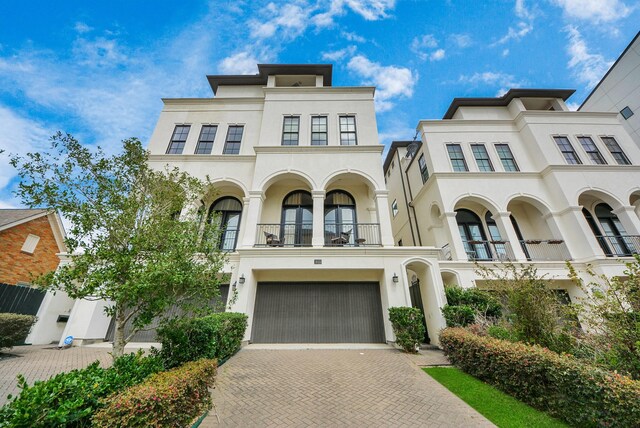 314 W Clay St, Houston, TX 77019 - view of front facade with a balcony, stucco siding, decorative driveway, and a garage