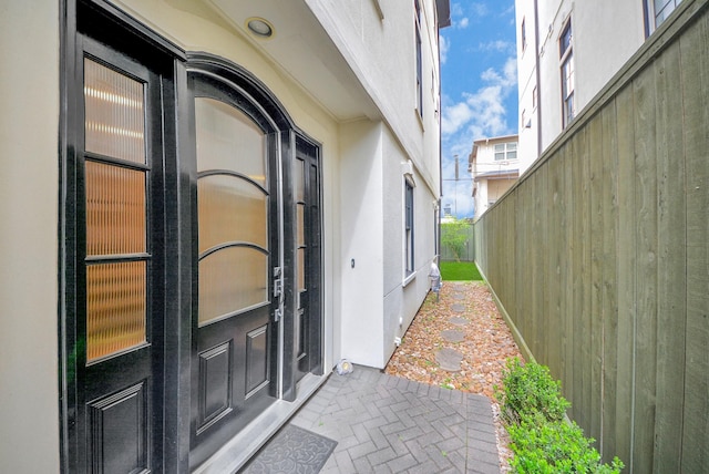 entrance to property featuring fence and stucco siding