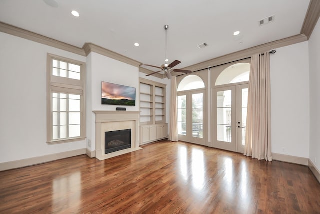 unfurnished living room featuring a fireplace, visible vents, ornamental molding, wood finished floors, and baseboards