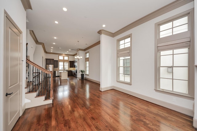 foyer entrance featuring dark wood-style flooring, a notable chandelier, ornamental molding, baseboards, and stairs