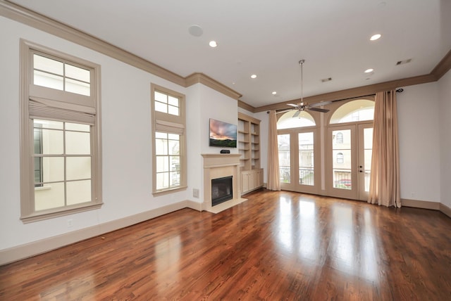 unfurnished living room featuring baseboards, a fireplace with flush hearth, wood finished floors, crown molding, and recessed lighting