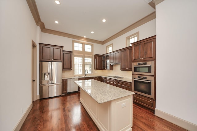 kitchen with stainless steel appliances, dark wood-style flooring, a sink, dark brown cabinets, and a center island