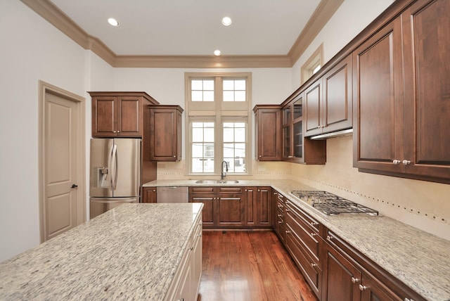 kitchen featuring glass insert cabinets, appliances with stainless steel finishes, dark wood-type flooring, crown molding, and a sink