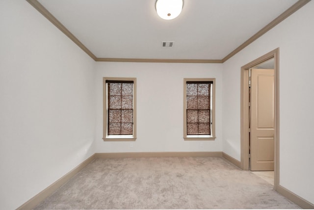 unfurnished room with visible vents, baseboards, crown molding, and light colored carpet