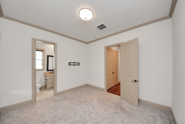 unfurnished bedroom with baseboards, visible vents, connected bathroom, ornamental molding, and carpet floors