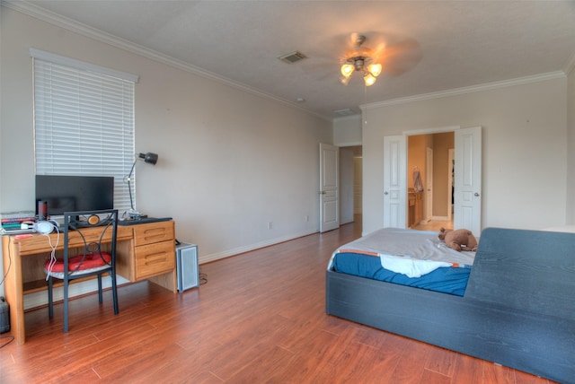 bedroom featuring ornamental molding, visible vents, baseboards, and wood finished floors