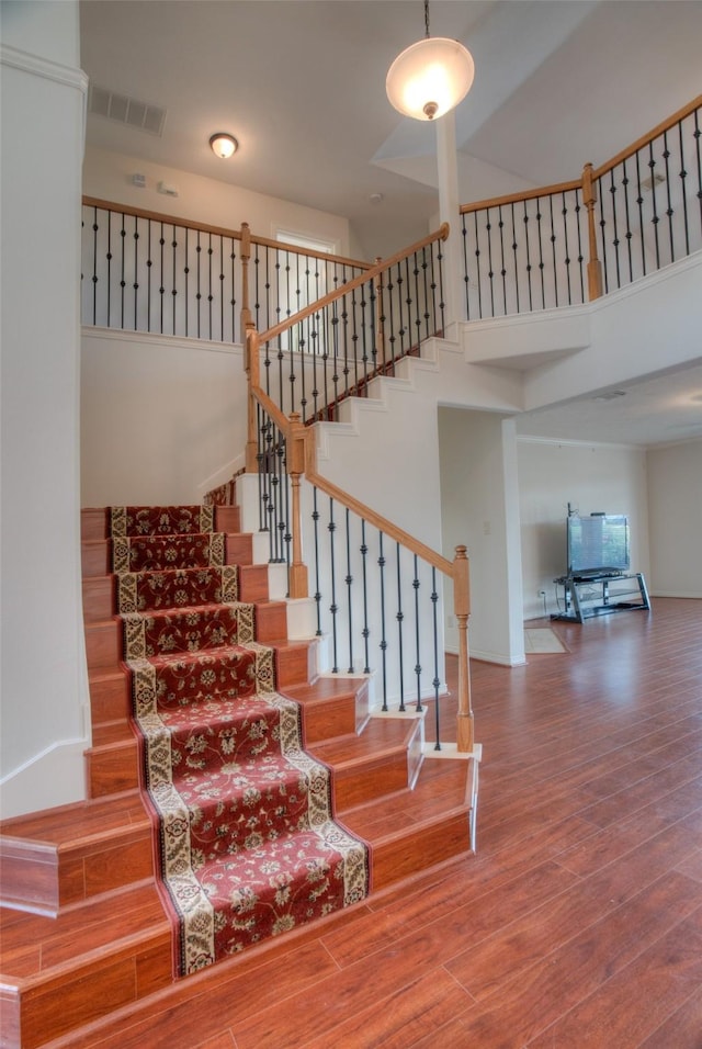 staircase featuring a high ceiling and wood finished floors