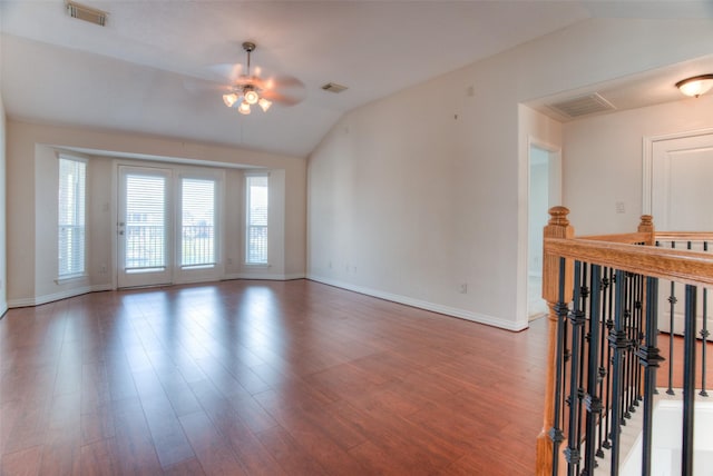 spare room with lofted ceiling, wood finished floors, visible vents, and baseboards