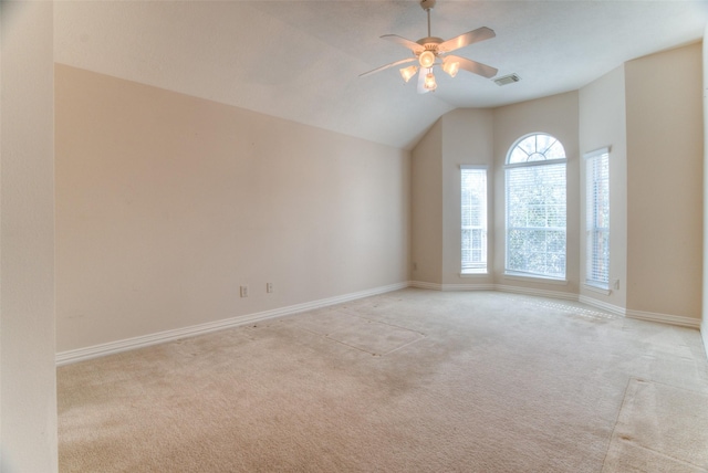 spare room featuring light colored carpet, visible vents, vaulted ceiling, ceiling fan, and baseboards