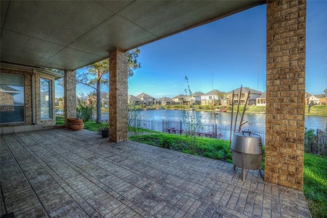 view of patio / terrace with a water view, a residential view, and fence